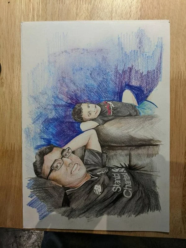 Color pencil drawing of two people lying on a couch, a man wearing glasses and a black shirt with "Stay Chillin" text, and a boy in a black hoodie with a graphic, with a blue and purple background.