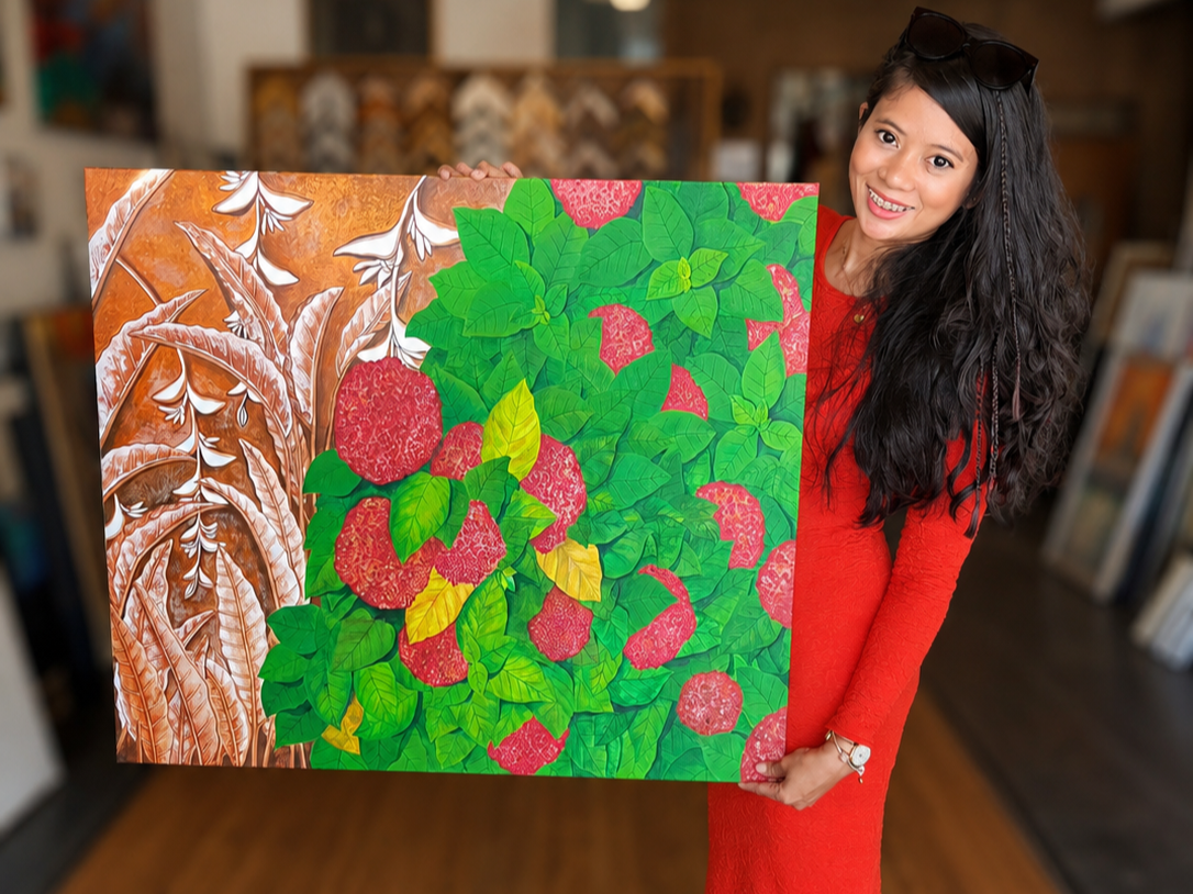 Woman with long black hair wearing a red dress and sunglasses on her head, smiling and holding a large colorful painting of raspberries with green leaves, in an art gallery.