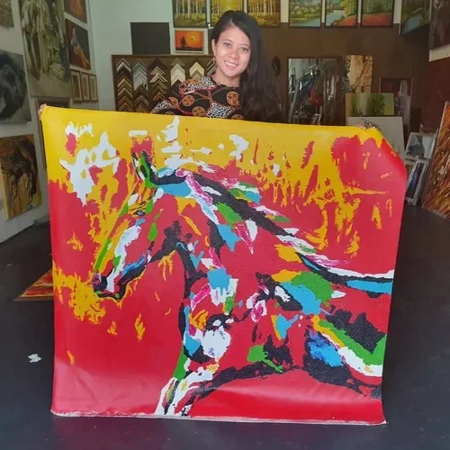 A woman holding a colorful abstract painting inside an art gallery.