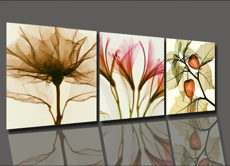 Triptych of botanical artwork featuring pressed leaves and flowers in earthy tones, mounted on a gray wall.