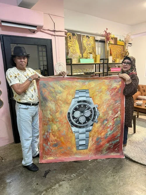 Two women holding a painted fabric with a large printed image of a wristwatch, inside a room with shelves, framed art, and furniture.