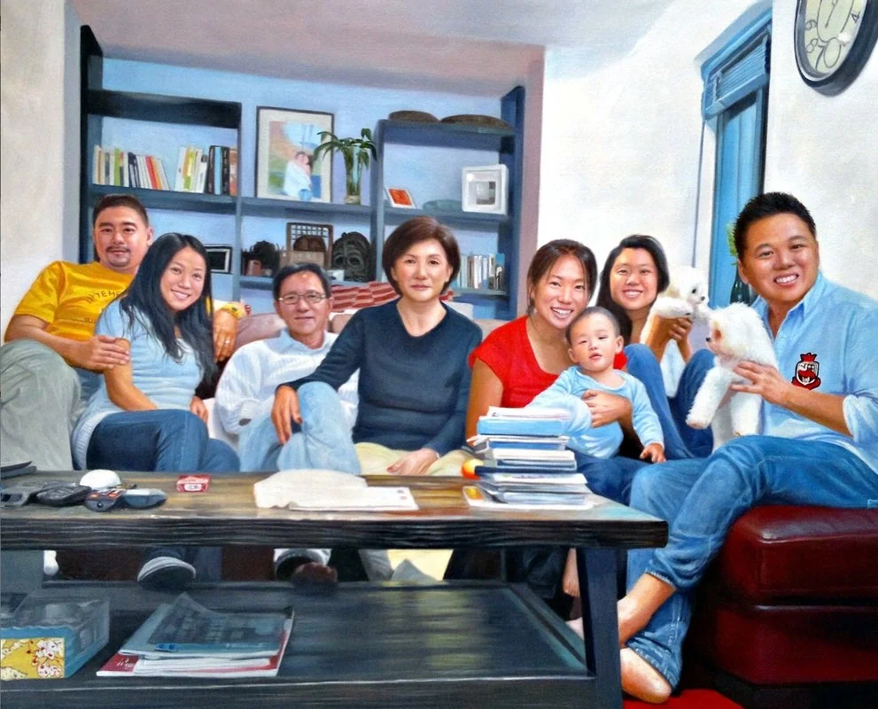 A group of nine family members sitting on a couch and chairs in a living room, smiling and posing for a photo, with two small white dogs being held by a man and a woman.