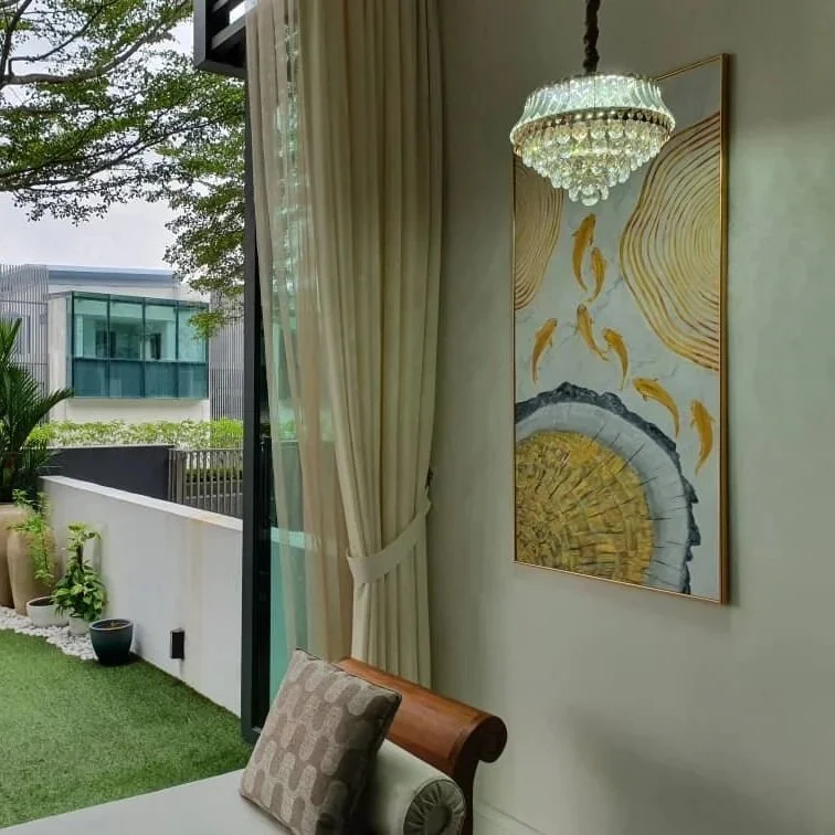 A living room with a large window and curtain, featuring a modern chandelier, abstract fish artwork, and a glimpse of a balcony garden with potted plants.