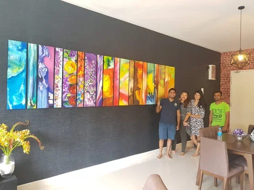 Four people standing in front of a colorful abstract painting on a black wall in a modern room.