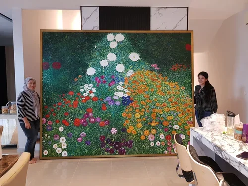 Two women standing beside a large colorful abstract floral painting on an easel in a modern interior space.