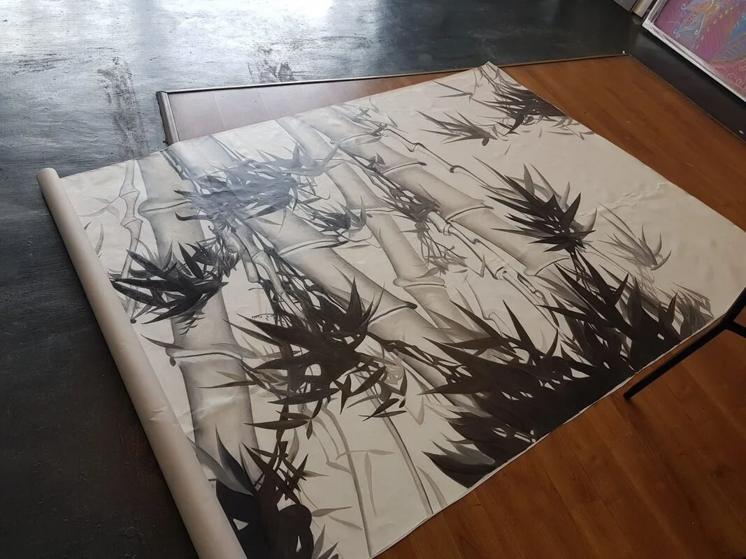 Large scroll of artwork depicting bamboo plants in black and white, partially unrolled on a table.
