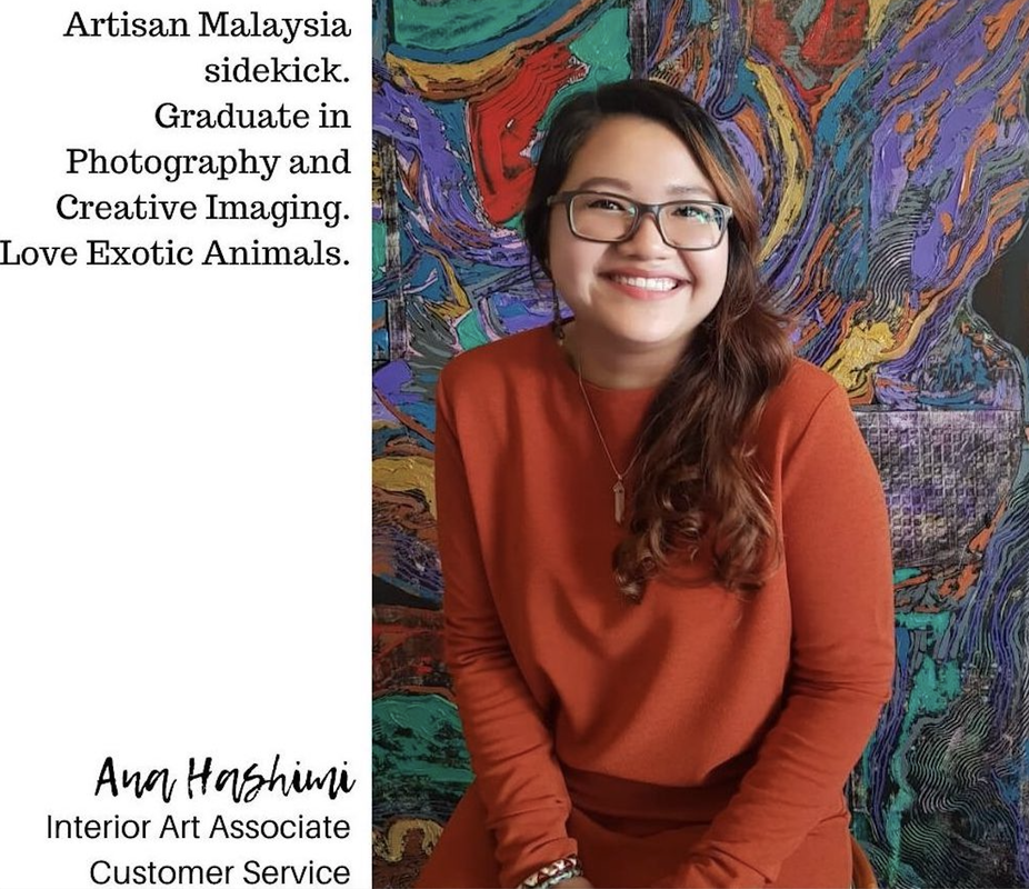 A smiling woman with glasses wearing an orange sweater, sitting in front of a colorful abstract artwork background.
