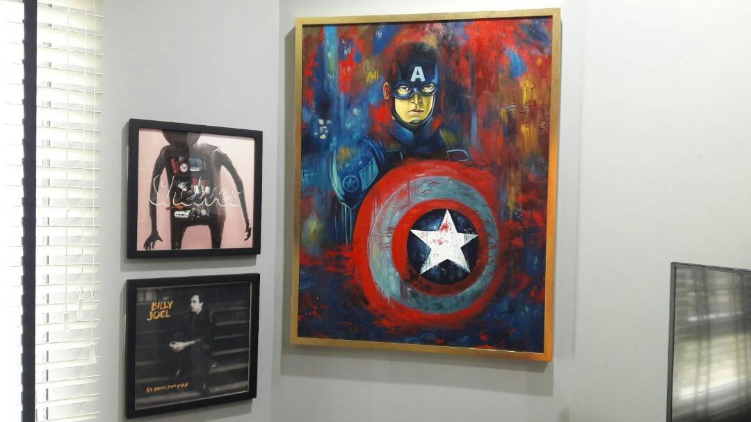 Colorful painting of Captain America holding his shield, wearing his blue costume with a yellow face mask, on a multicolored abstract background.