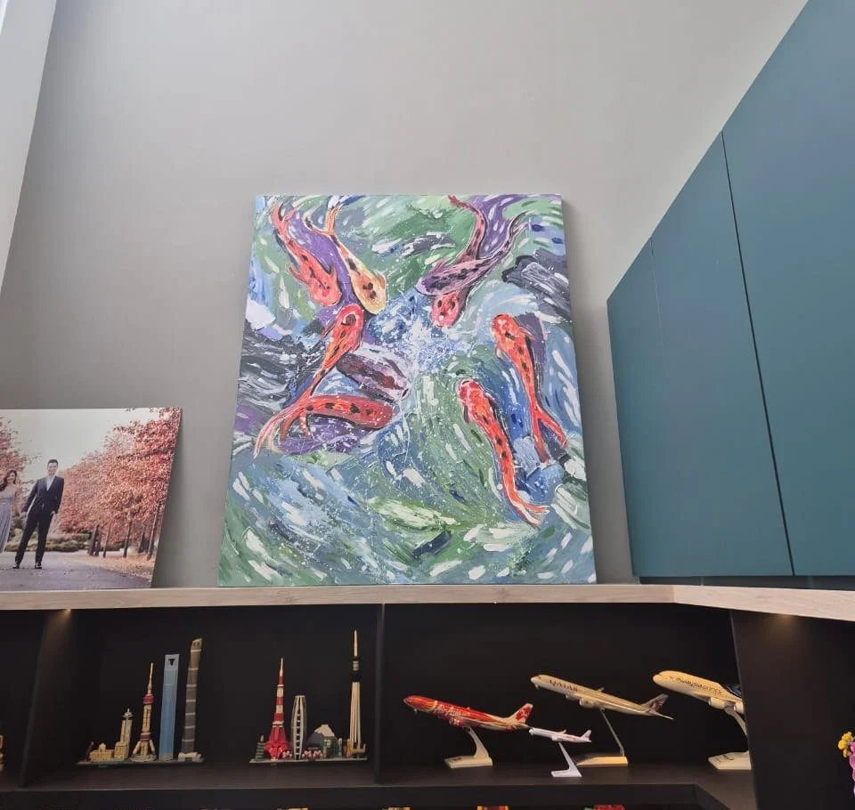 A colorful painting of koi fish swimming in water, displayed on a wall in an interior space.