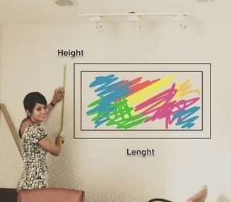 A woman standing next to a whiteboard with a colorful, scribbled drawing inside a black rectangle, labeled 'Height' and 'Length'.