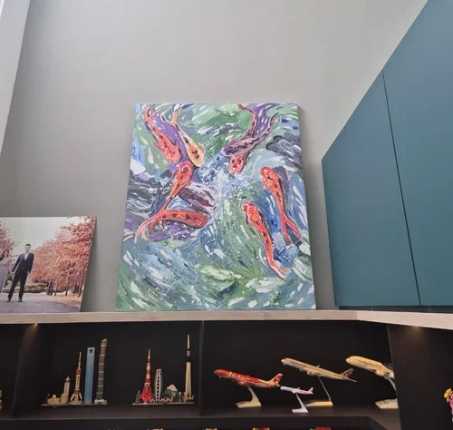 A colorful painting of koi fish swimming in water, displayed on a wall in an interior space.
