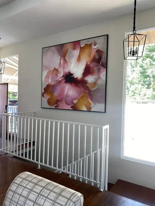 Interior of a house with a large floral painting, a hanging light fixture, and a sliding glass door leading outside.