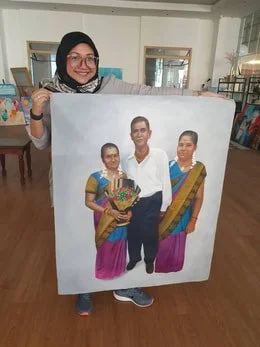 A woman holding a large photo of three people, two women in traditional clothing and a man in a white shirt, in a room with bookshelves.