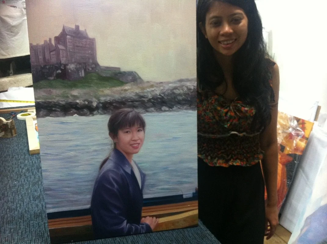 A woman holding a painting of herself by a body of water with a castle in the background, showing her seemingly standing in front of the painting.