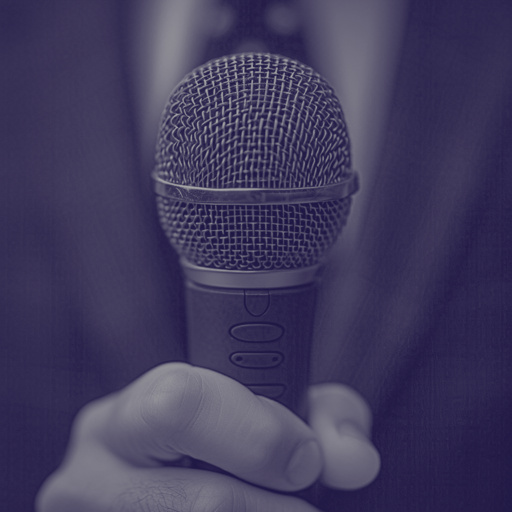 Un microphone tenu par une main, vue de face, en gros plan.