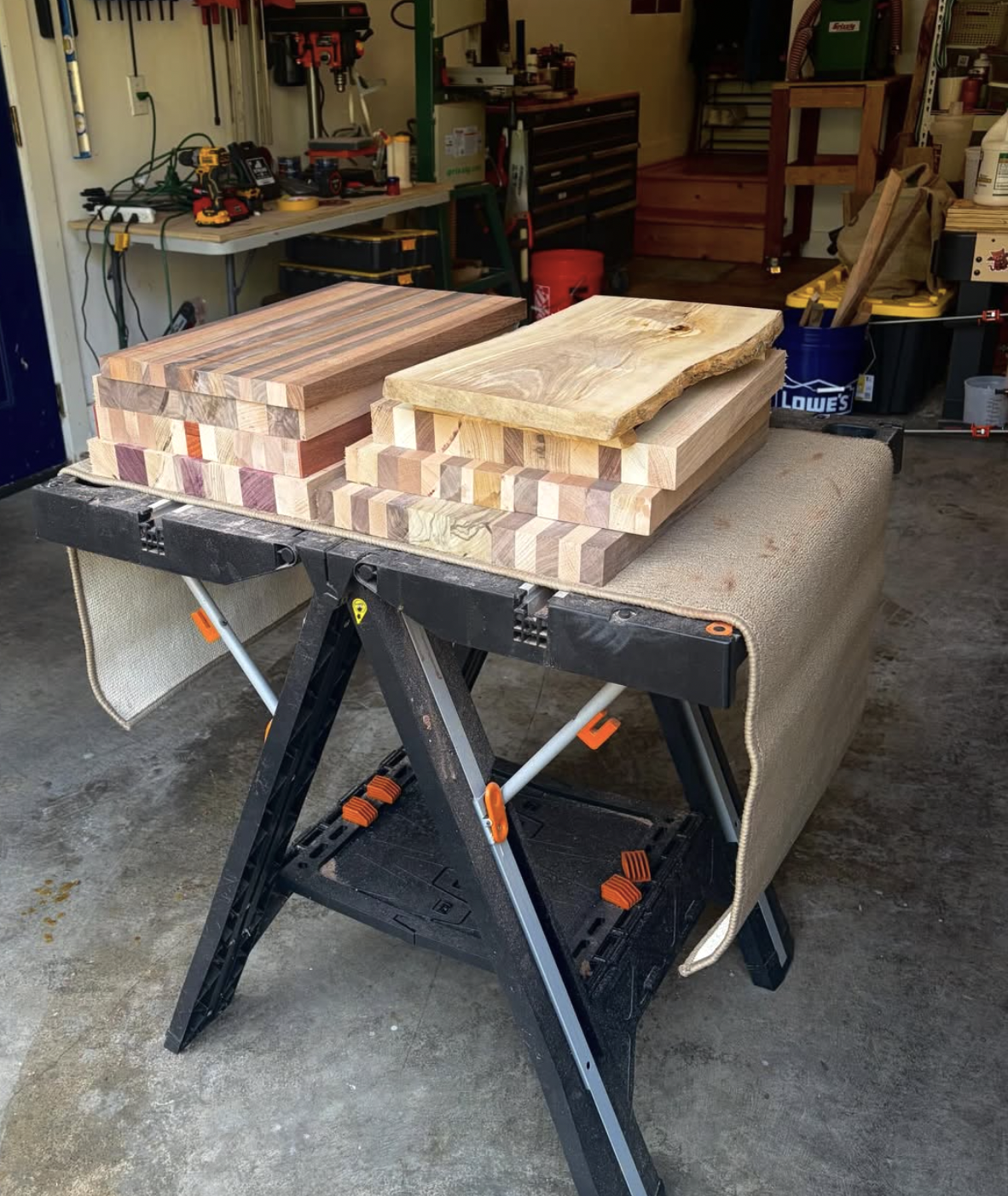 Colorful handcrafted wooden cutting boards stacked on a workbench in a garage workshop