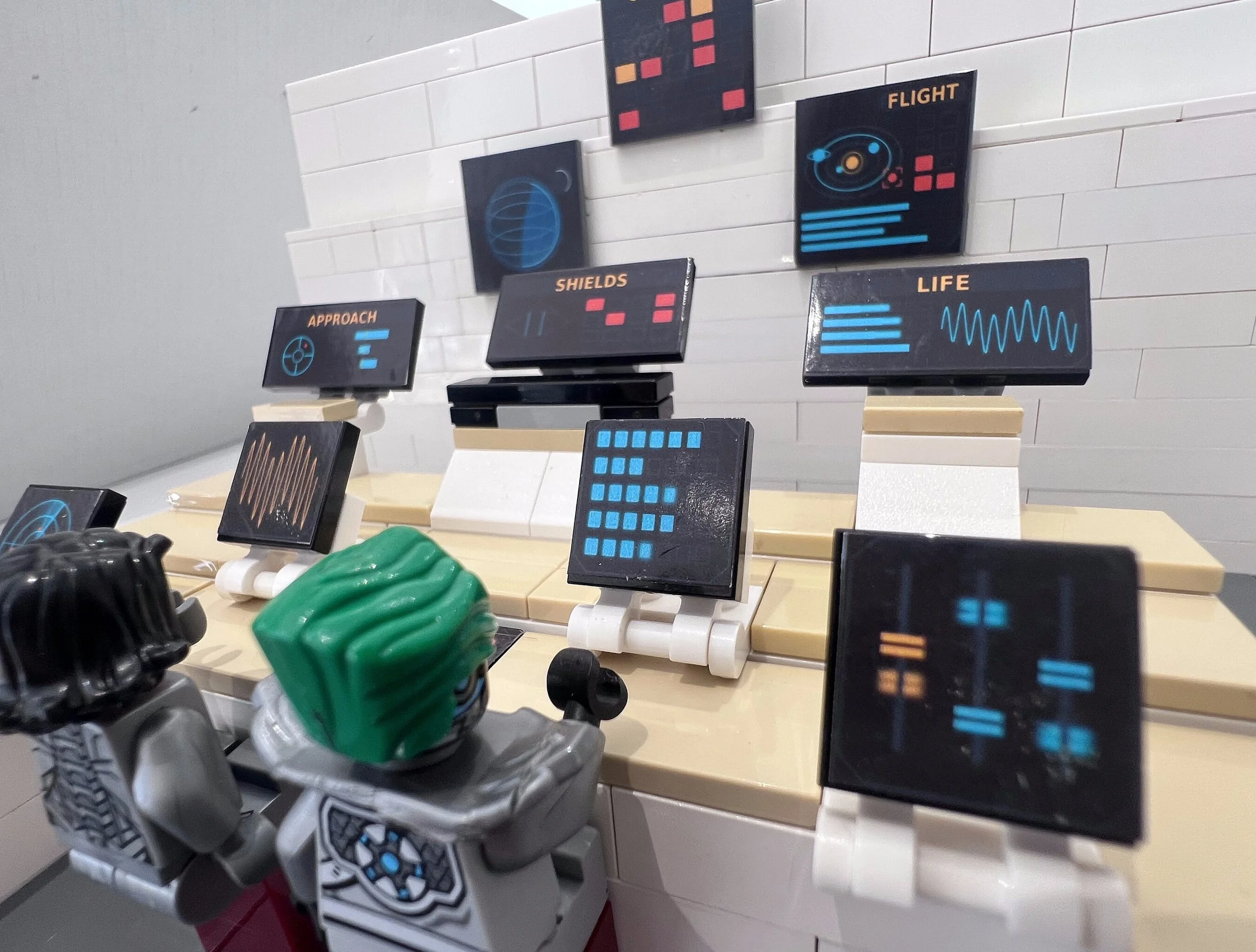 Close-up of LEGO control panel stickers applied to 2x2 and 2x4 black tiles, showing the screen artwork at real size.