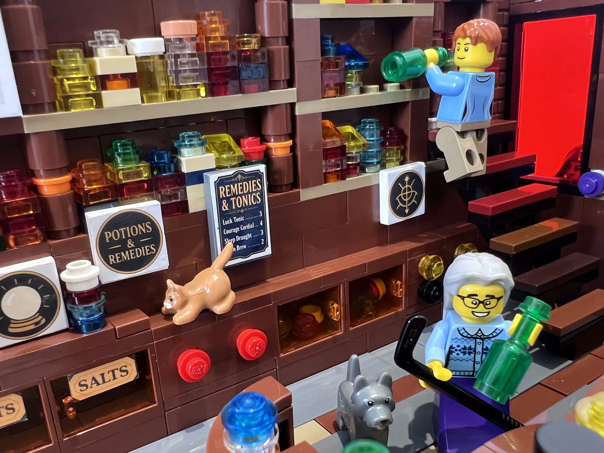 LEGO apothecary interior with an assistant on a ladder restocking the potion shelves above the counter