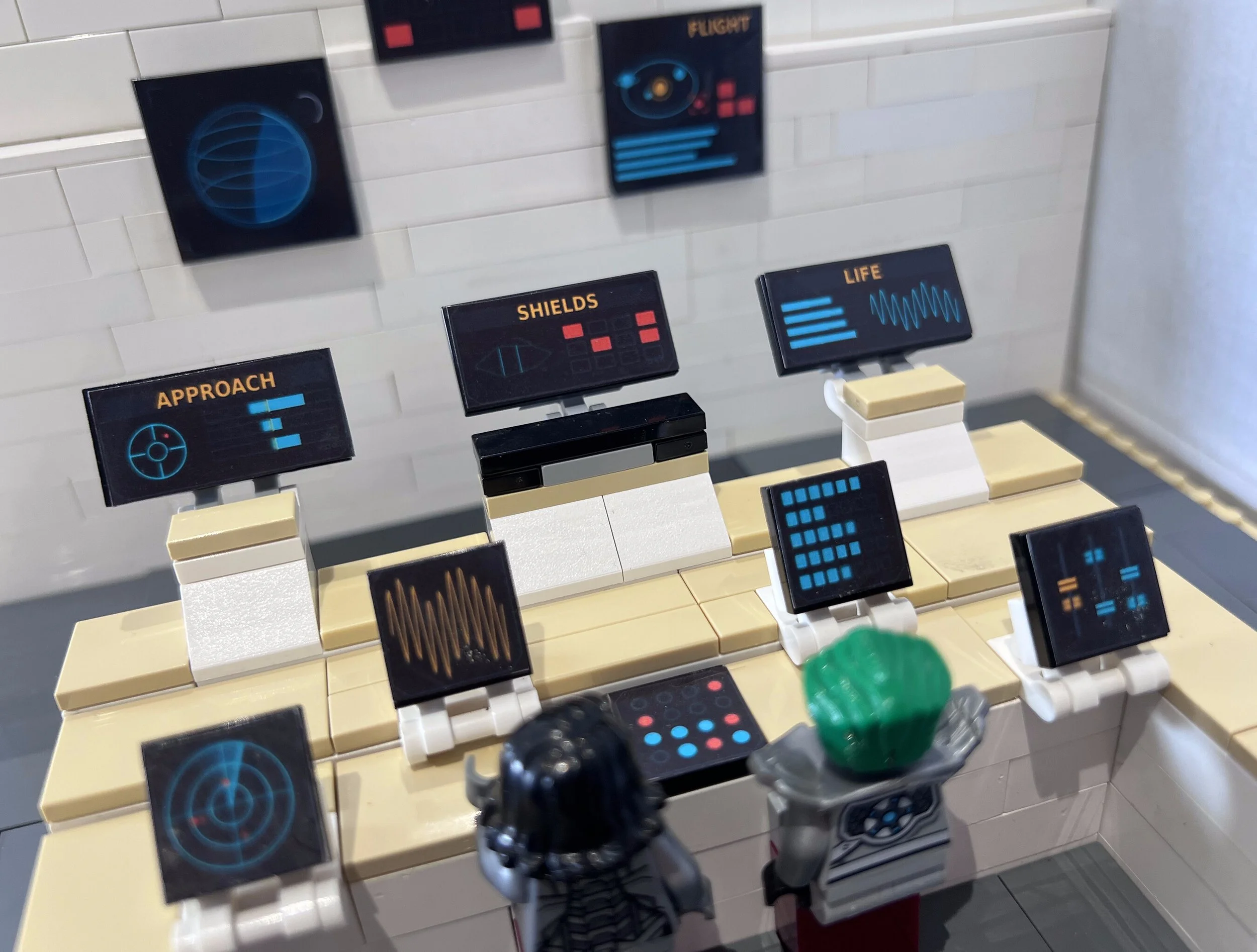 Angled view along the LEGO spaceship bridge console, showing the depth of the stepped desk and the panel stickers on each level.