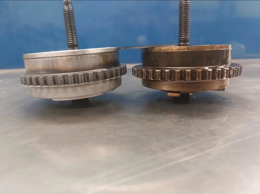 Two large metal gear wheels with bolts, placed on a metallic surface with a blue background.