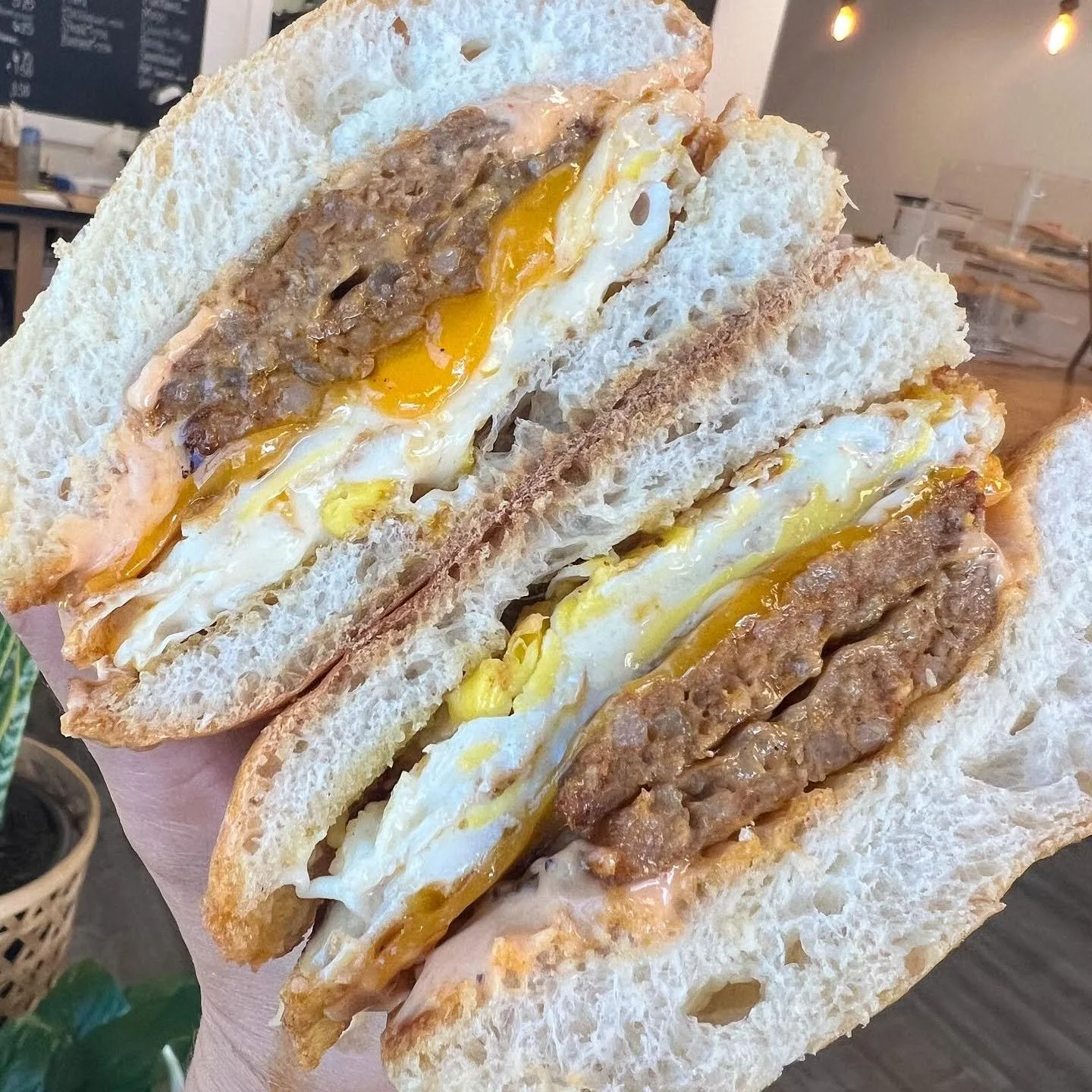 Close-up of a sandwich with fried egg, sausage, and bread slices.