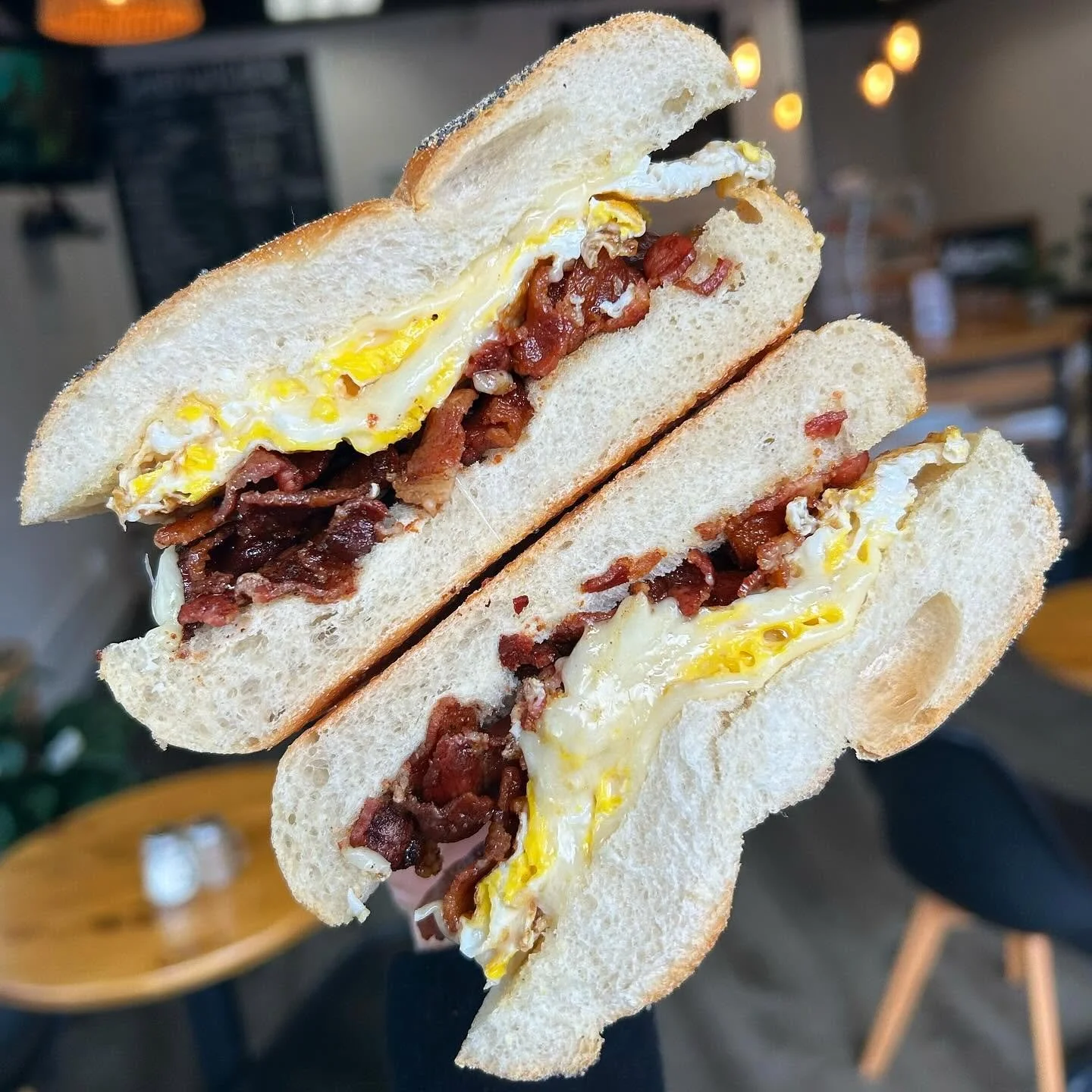 Half-cut bacon, egg, and cheese sandwich on white bread with a soft, fluffy texture and a slightly toasted crust.
