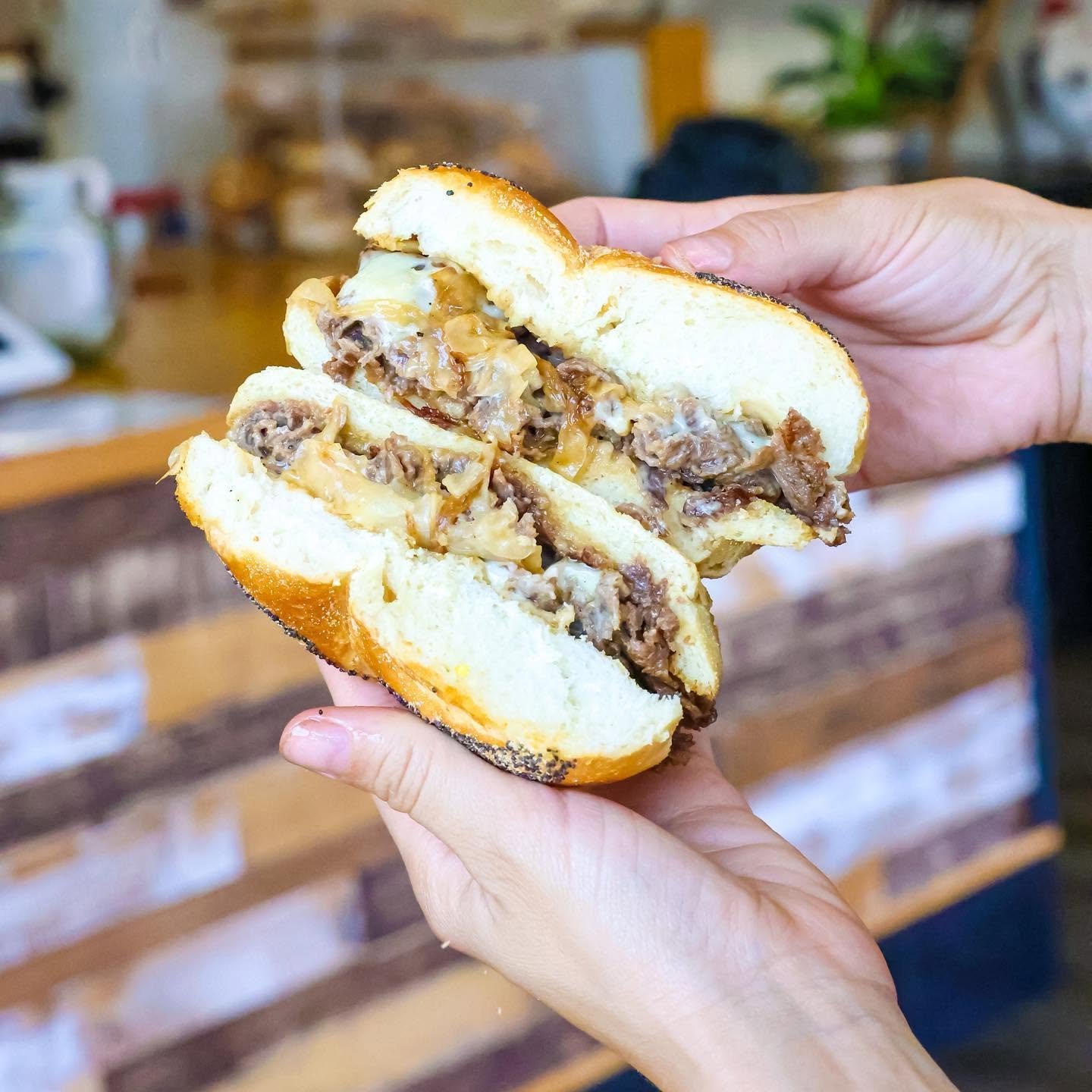 Close-up of a person holding a half-eaten burger with beef patty, melted cheese, onions, and bun.