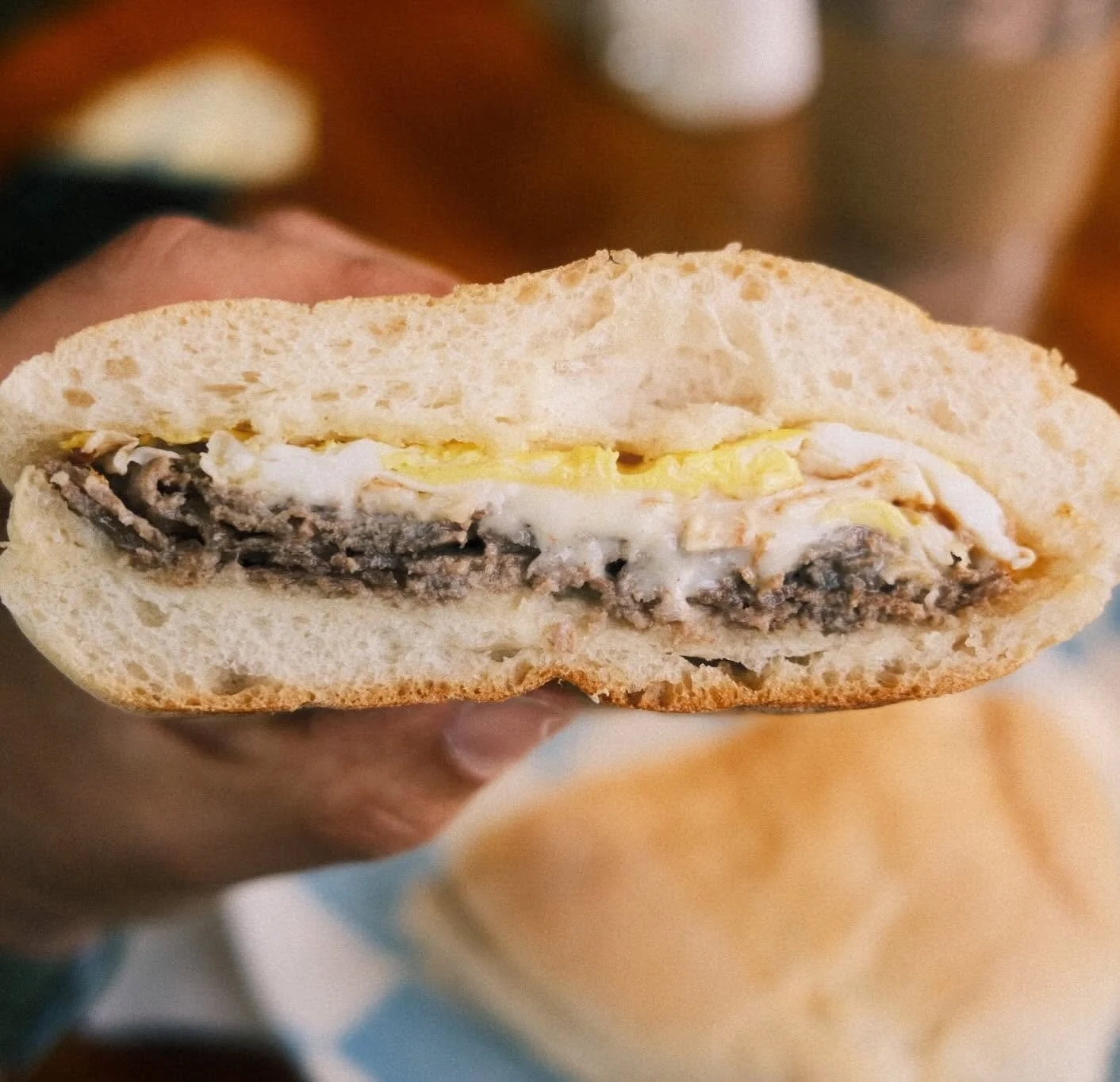Close-up of a sandwich with a soft bread roll filled with mushroom gravy, scrambled eggs, and mayonnaise.