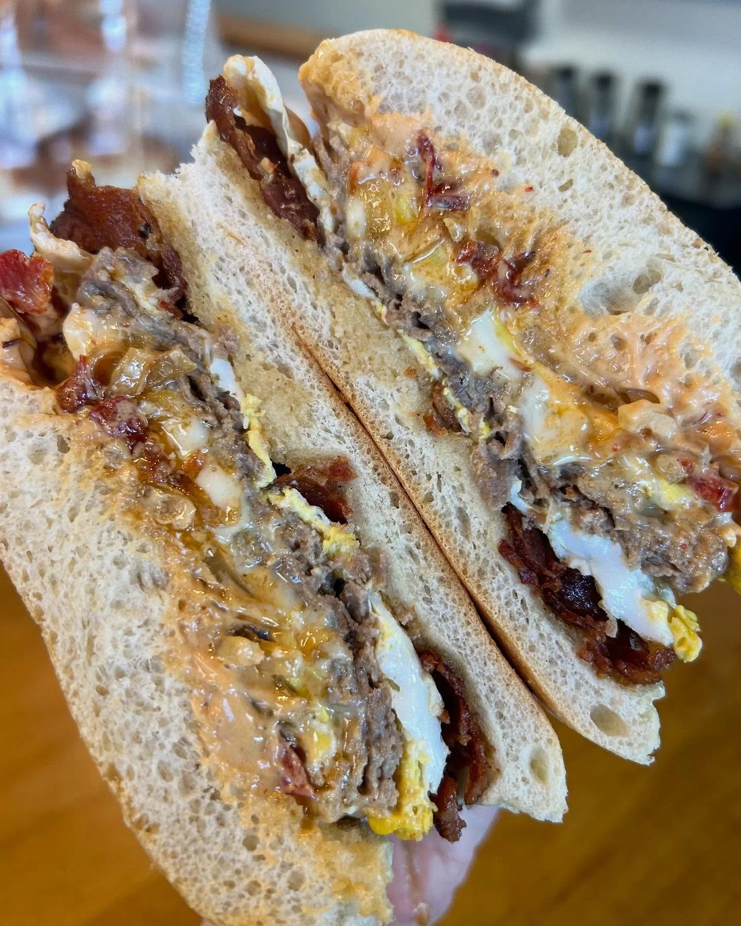 Cross-section of a sandwich with bread, bacon, eggs, and cheese inside.