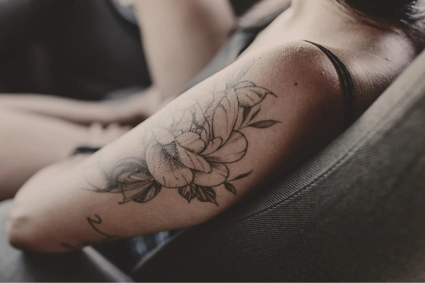 Close-up of a person's forearm featuring a detailed floral tattoo with multiple flowers and leaves.