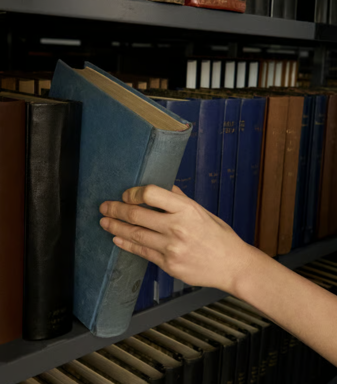 Hand selecting a book from a bookshelf
