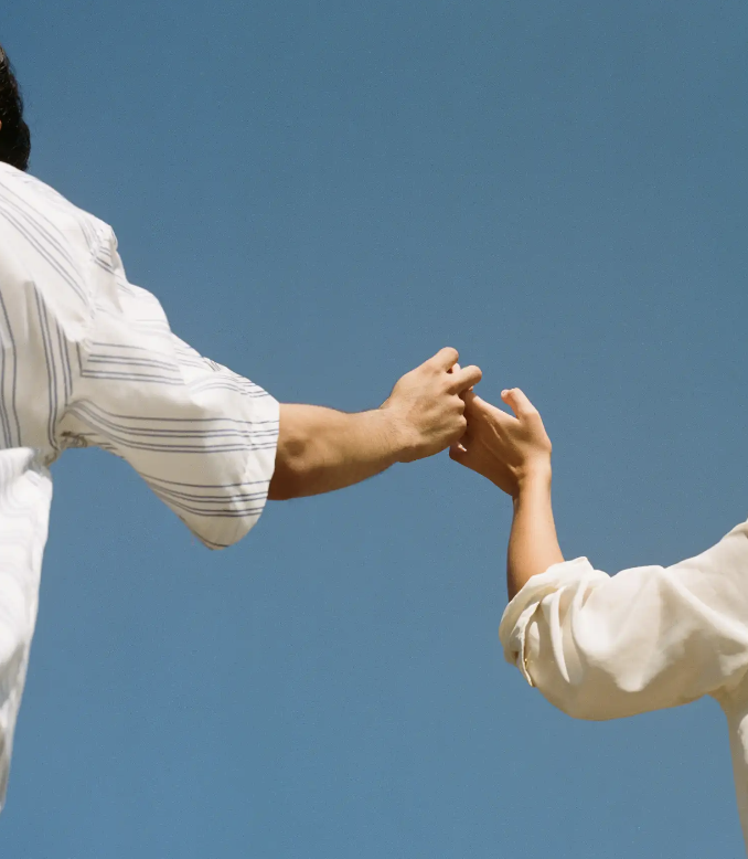 Two people holding hands against a blue background.