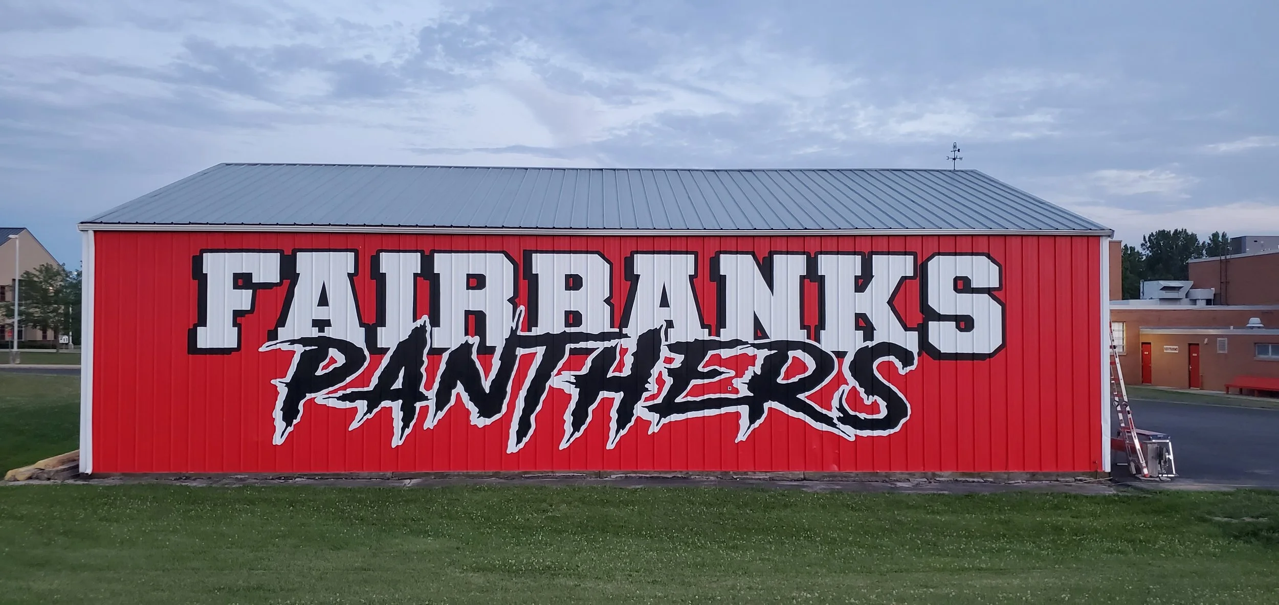Red barn with the words 'FARIBAUX PANTHERS' painted on it in large white and black letters, with a mountain graphic between the words.