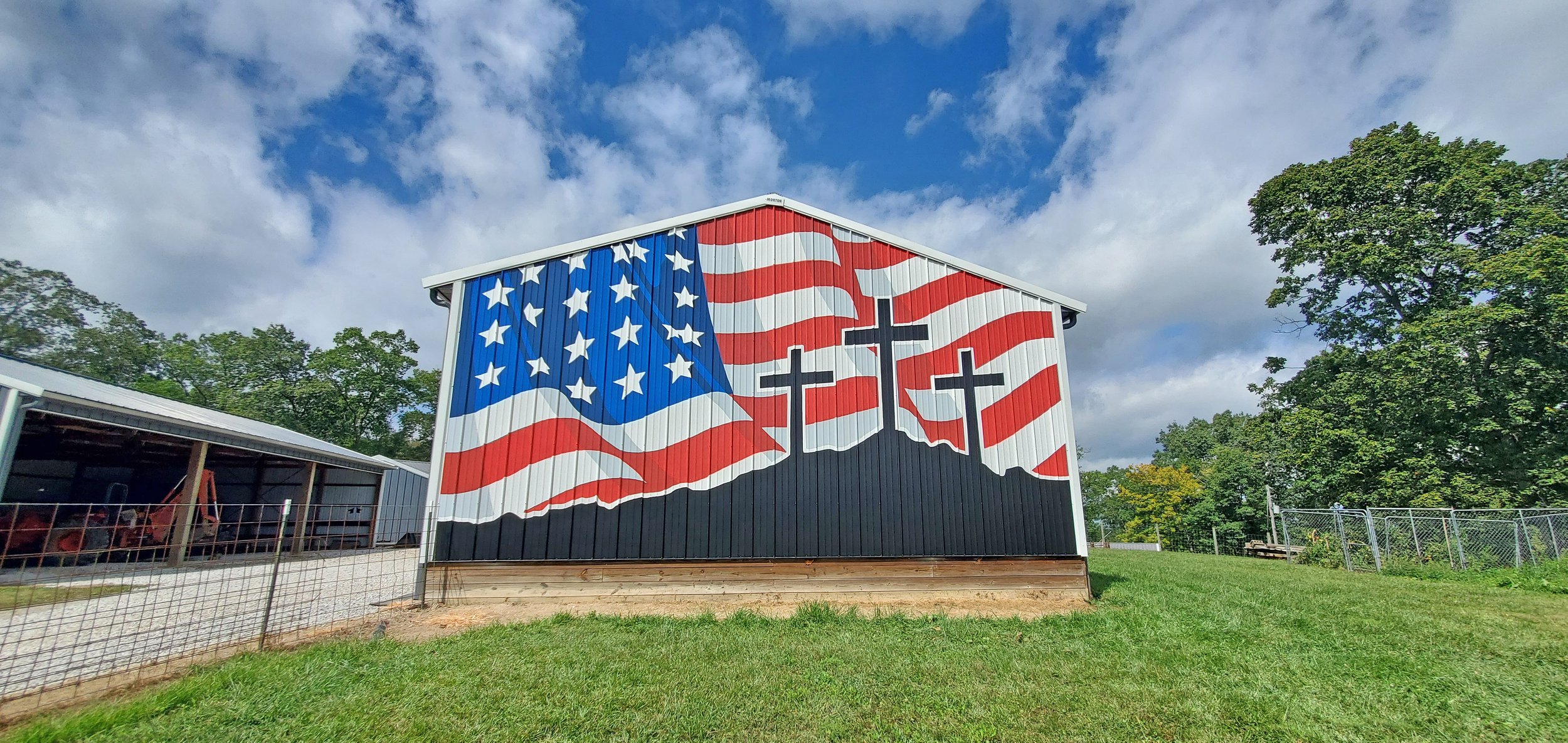 Barn painted with an American flag design, featuring stars and stripes, with three crosses in the center.