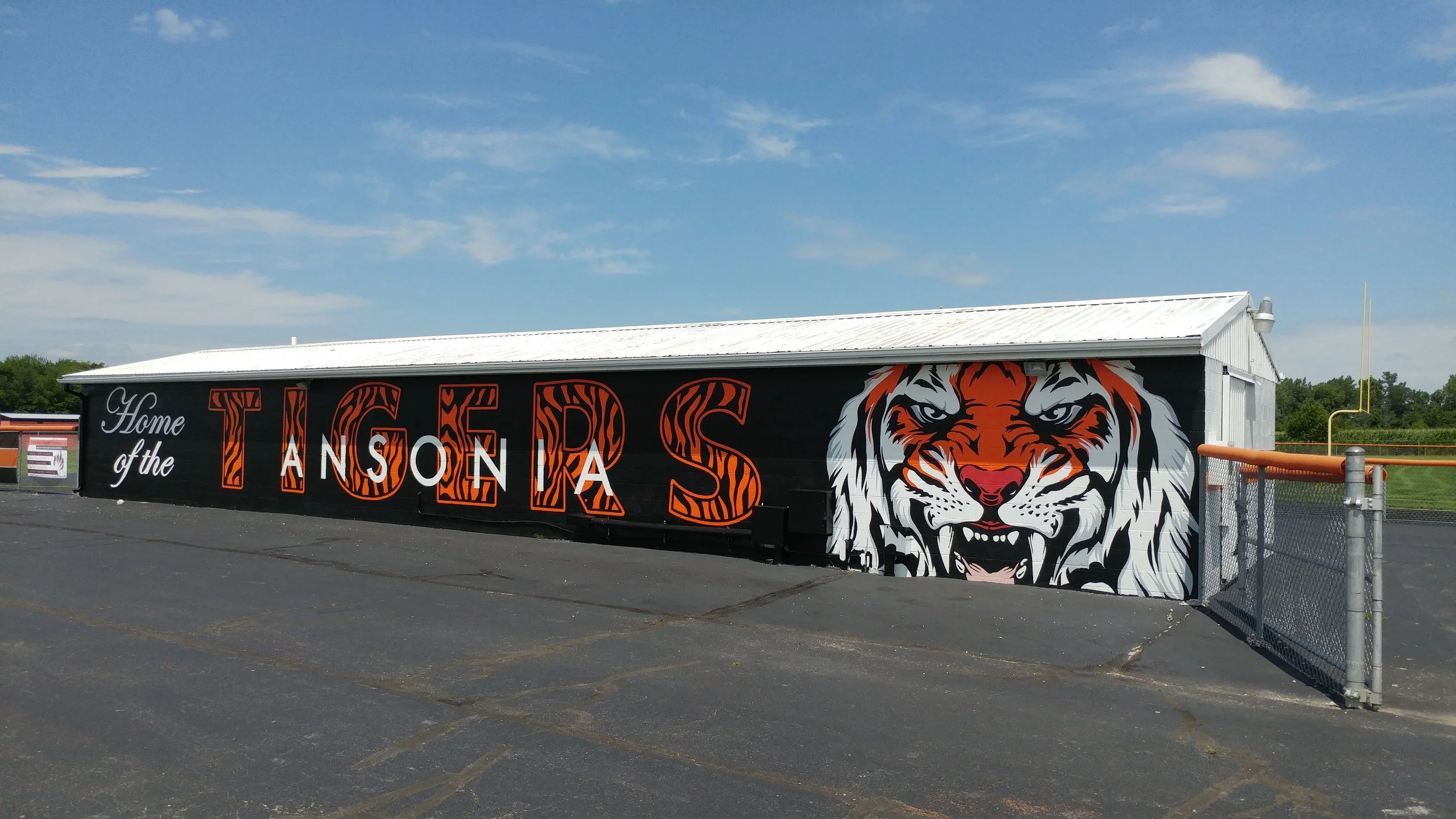 Outdoor stadium building painted with the words 'Home of the Tigers' and a fierce tiger mascot illustration on the side.