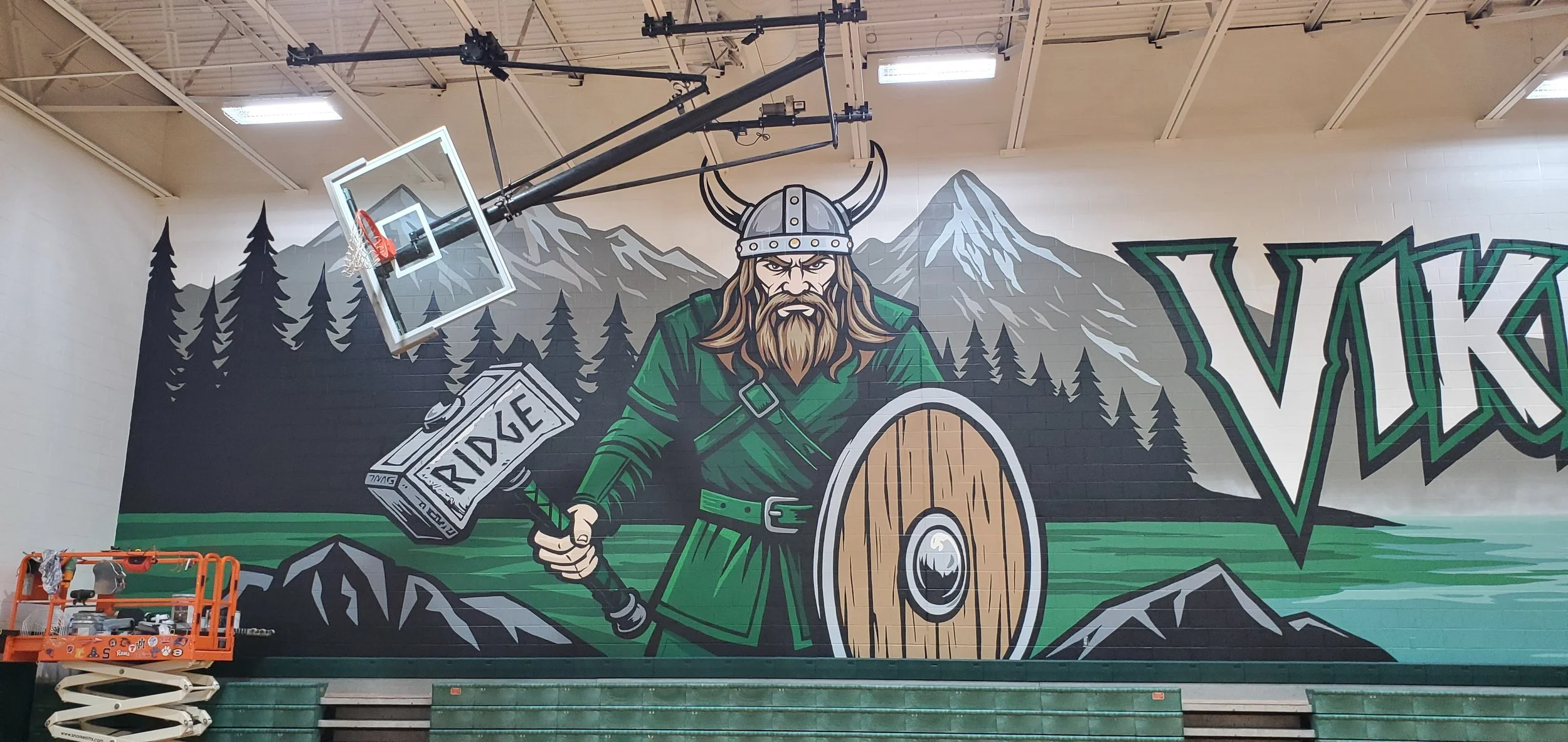 A large mural of a Viking warrior holding a battle axe labeled 'RIDE' and a round wooden shield, with mountains, pine trees, and the partial text 'VIK' in stylized lettering in the background.