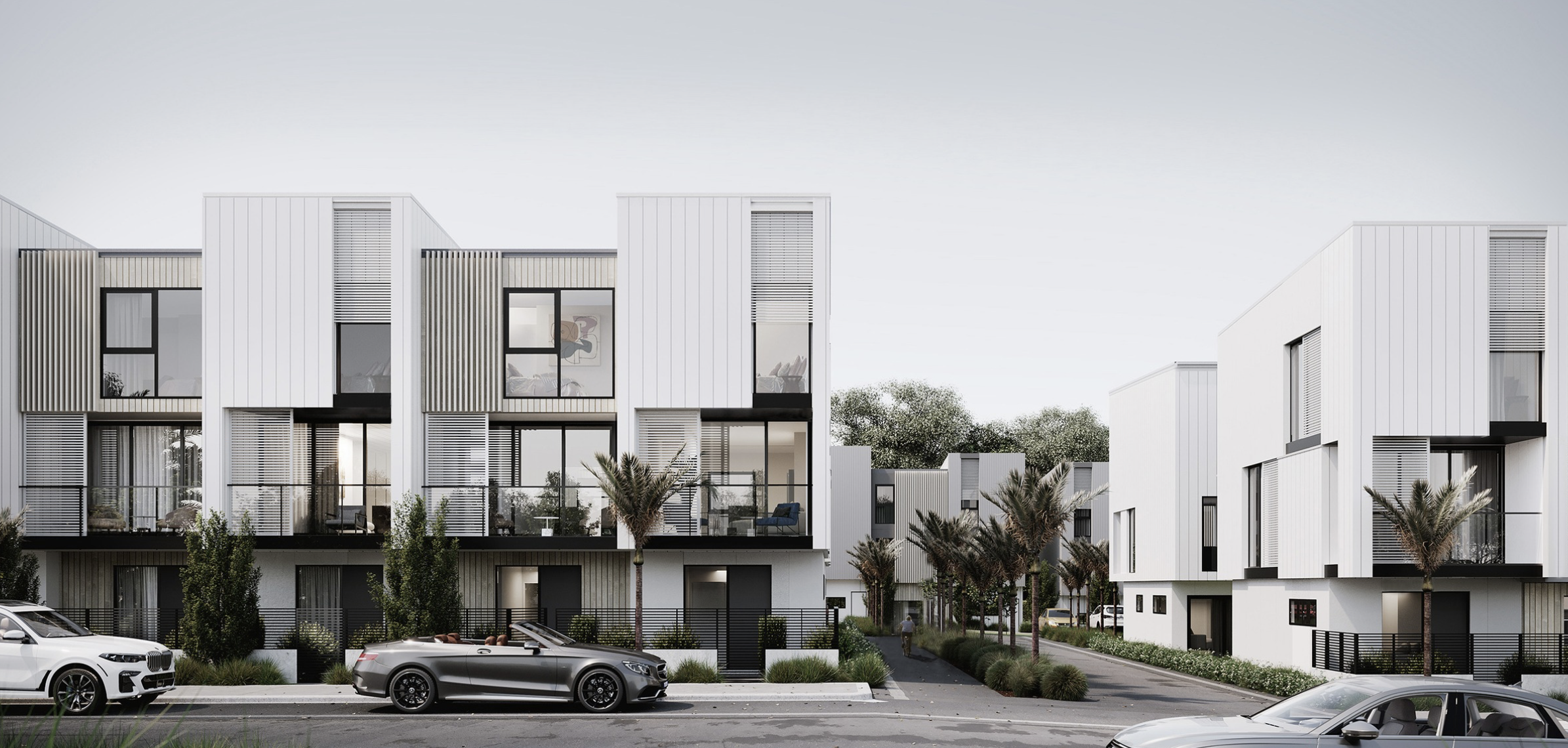 Modern white multi-story residential buildings with large windows, black railings, and small balconies, surrounded by palm trees and parked cars along the street.