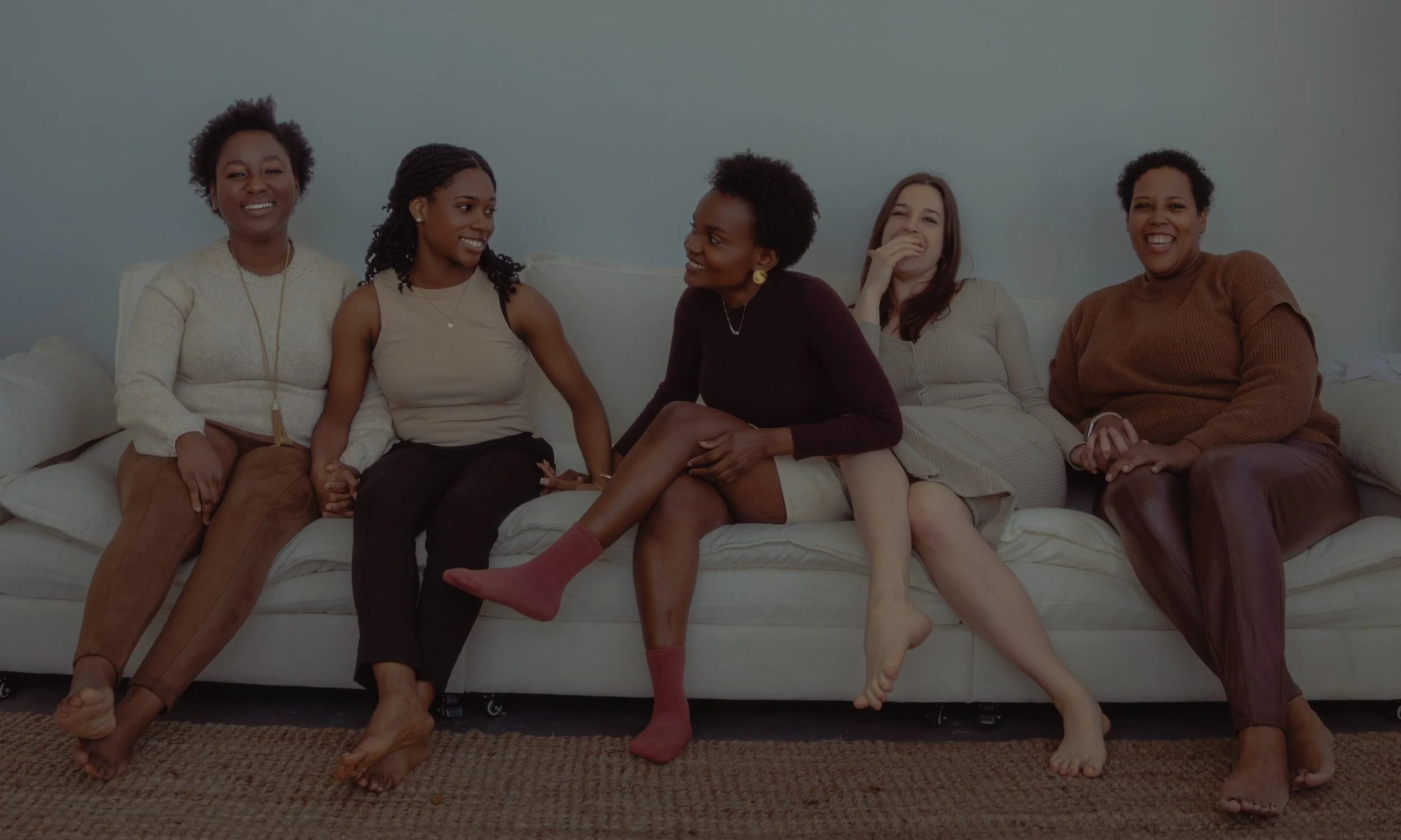 A small group of Ignite Sisterhood members sitting on a couch, smiling and laughing.