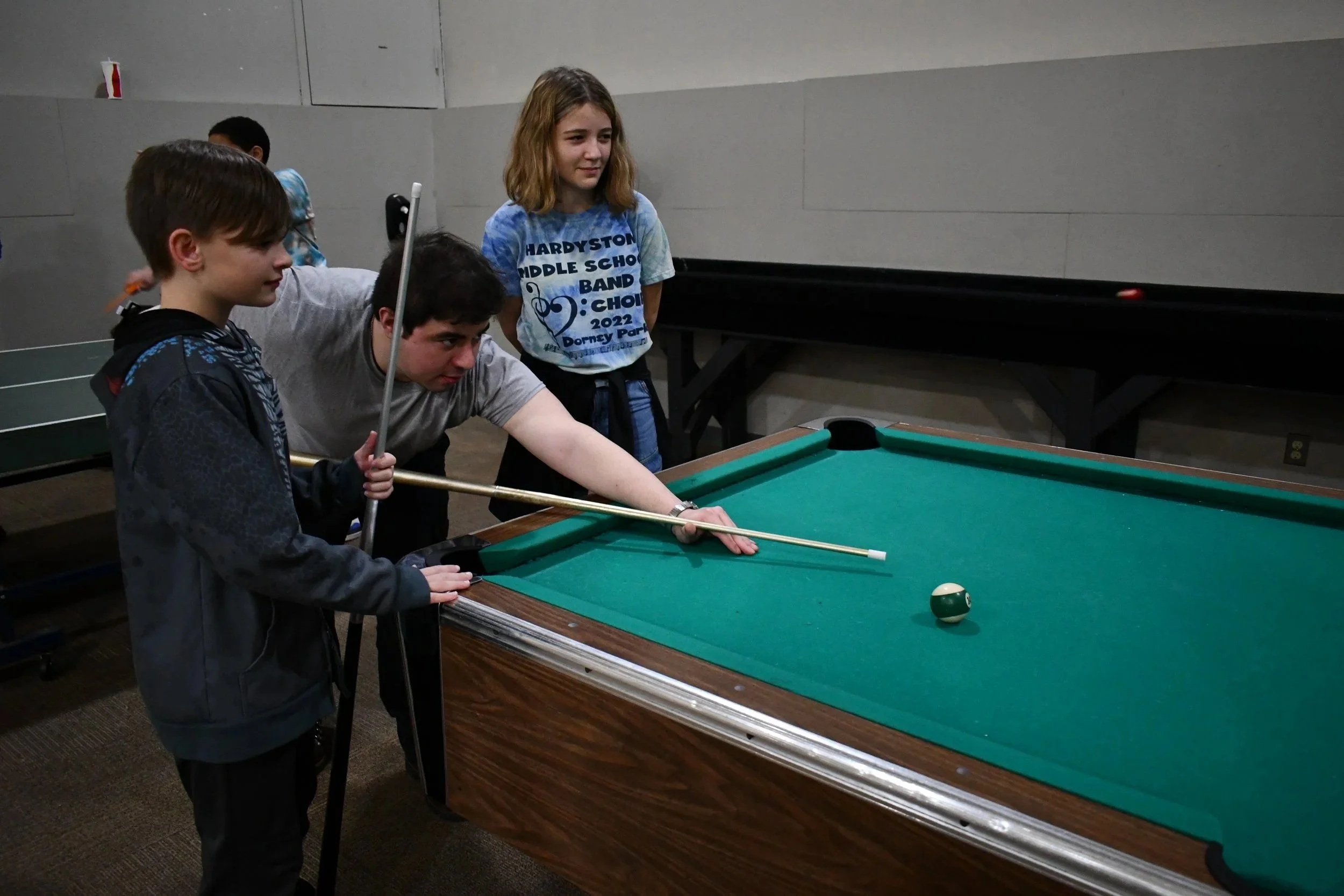 A group of teenagers playing pool.