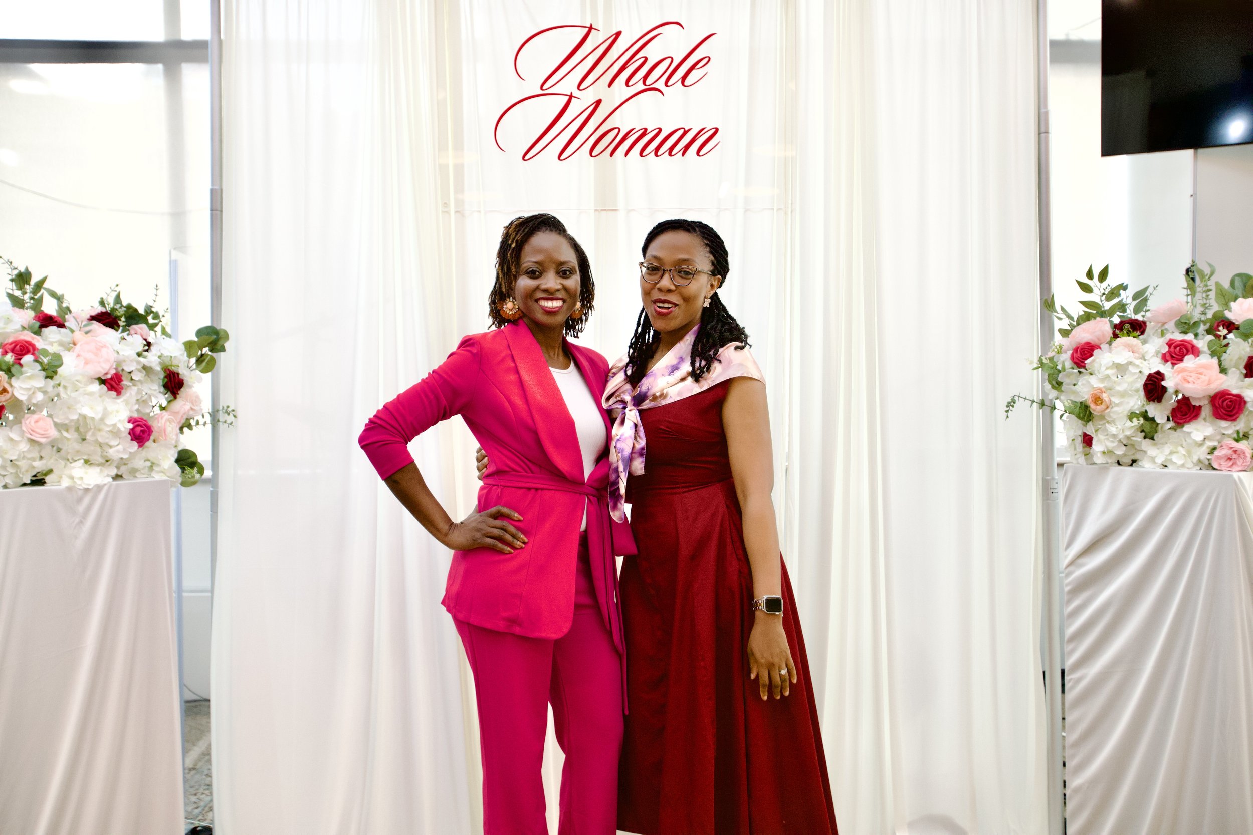 Two women side-by-side, posing for the camera with the 'Whole Woman' logo in the background.