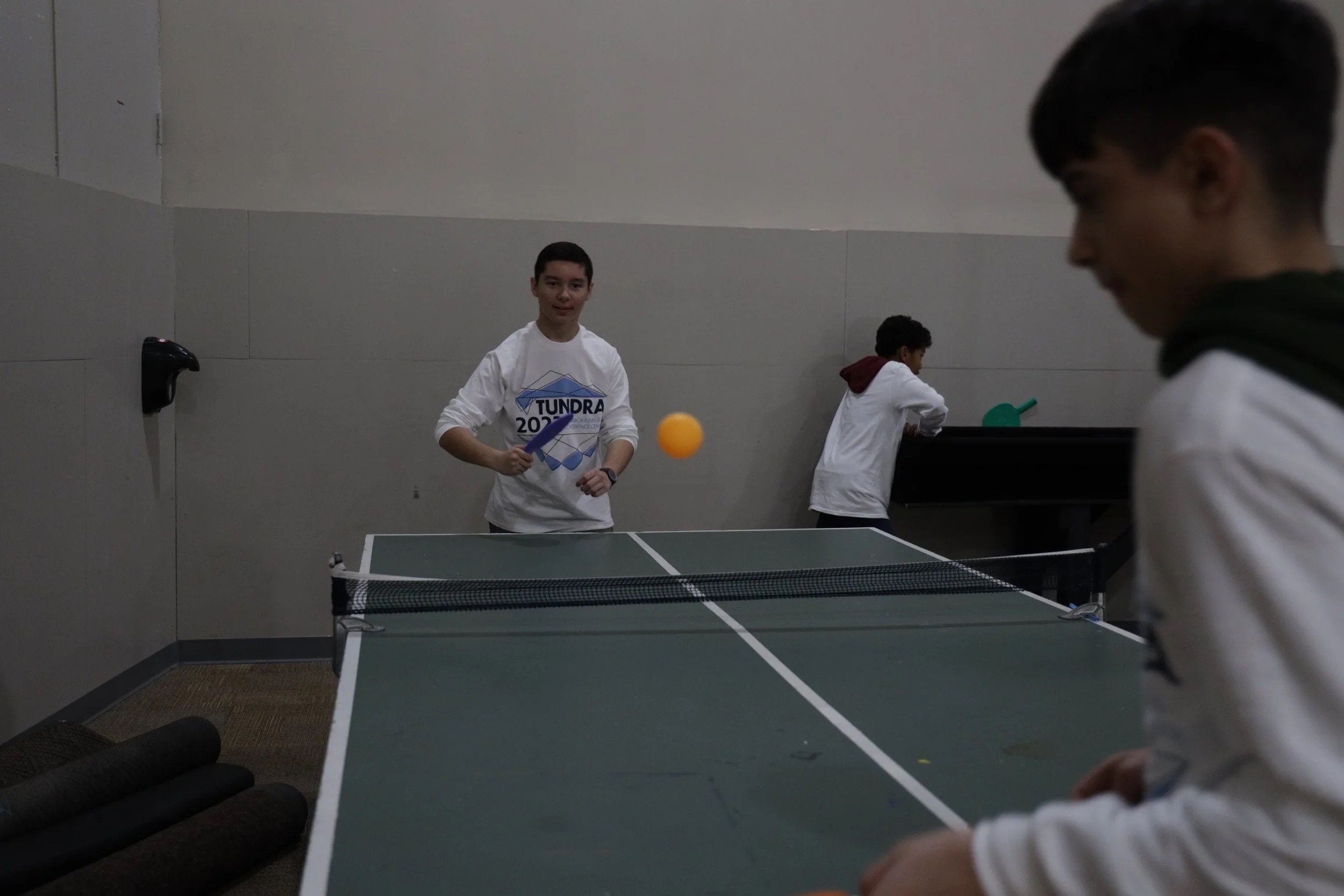 A group of kids playing ping-pong.