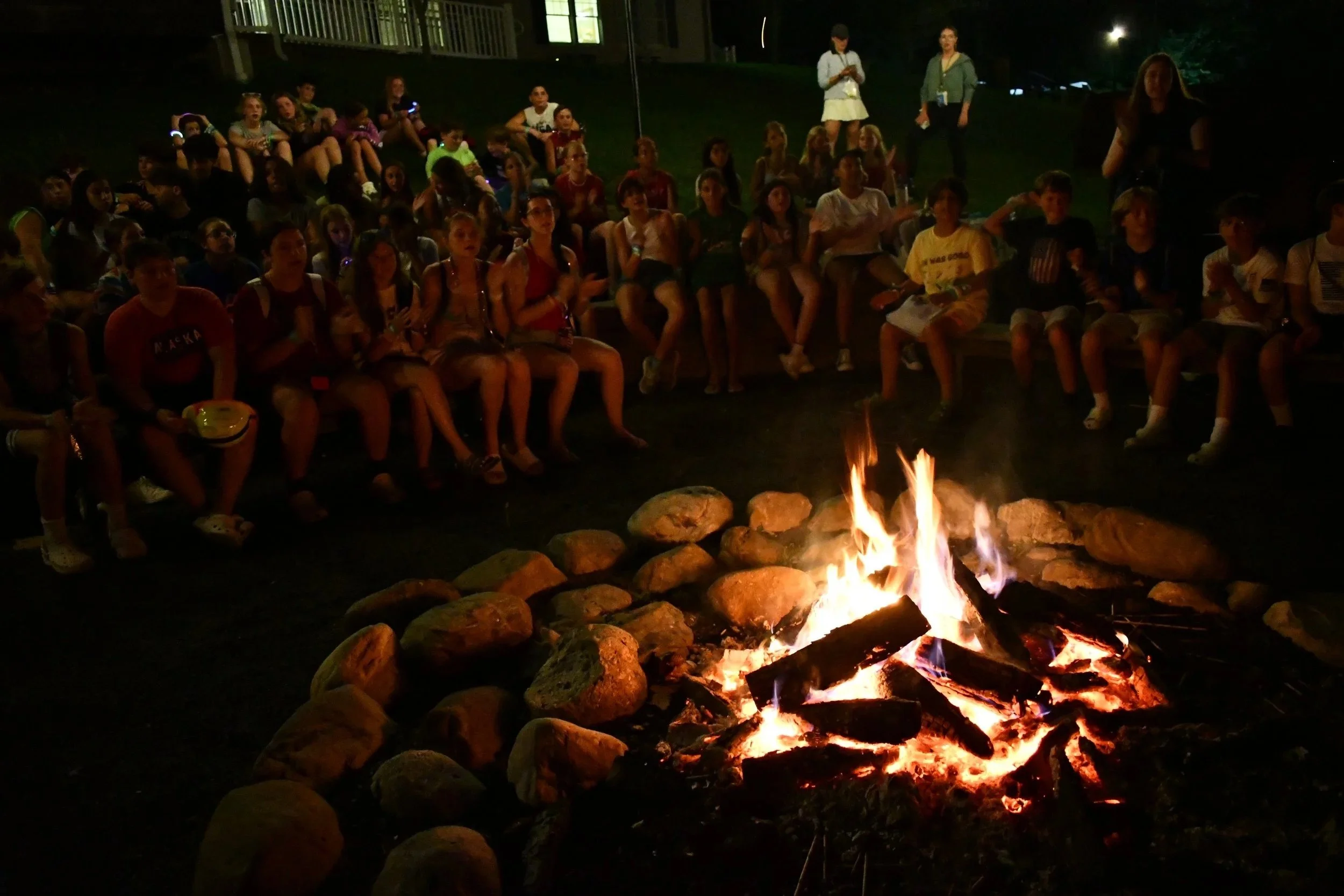 A large group of young people around a campfire.