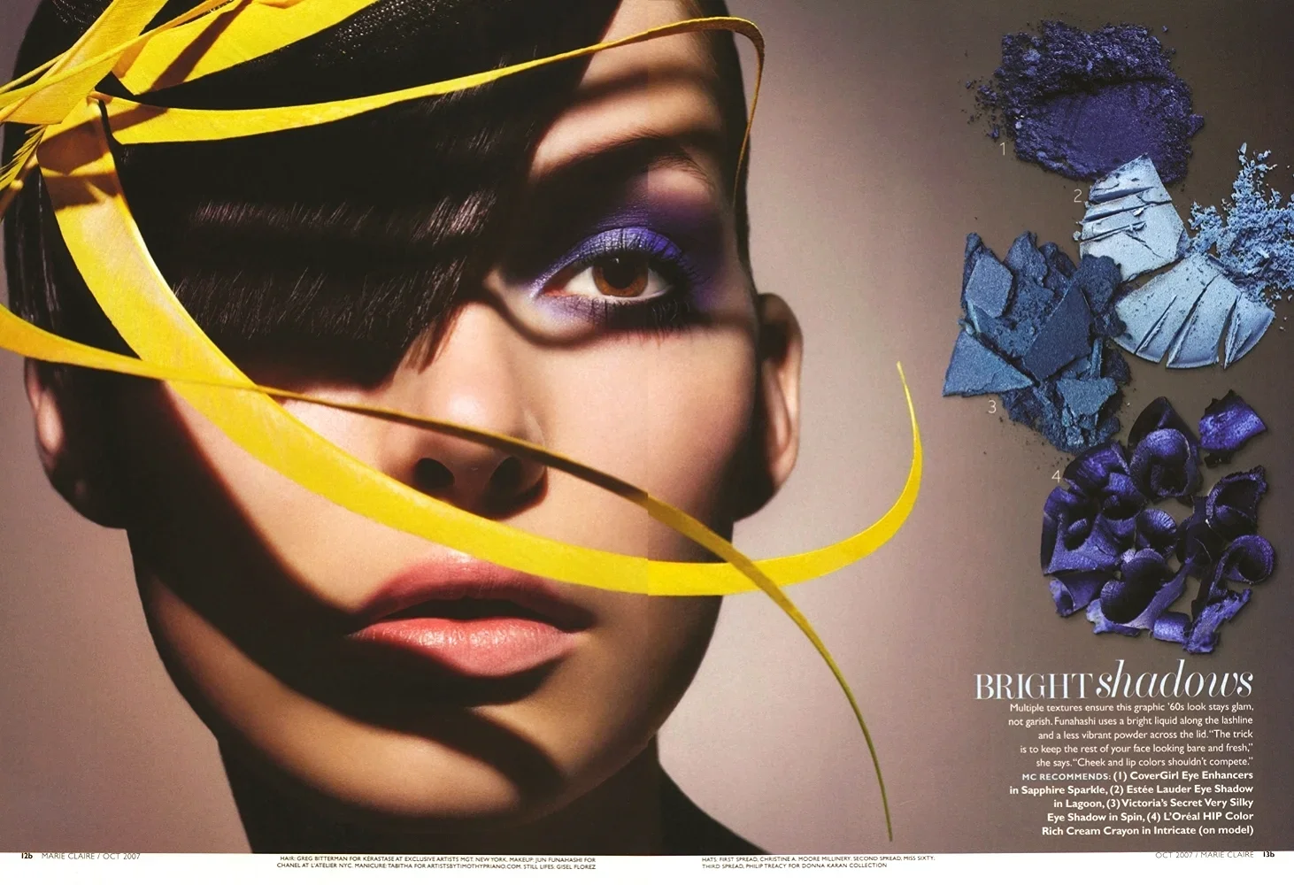Close-up of a woman's face with makeup, including purple eyeshadow, pink lipstick, and a yellow ribbon draped across her face. To the right, there are four sections of crushed eyeshadow powders in shades of purple and blue, labeled 1 through 4.