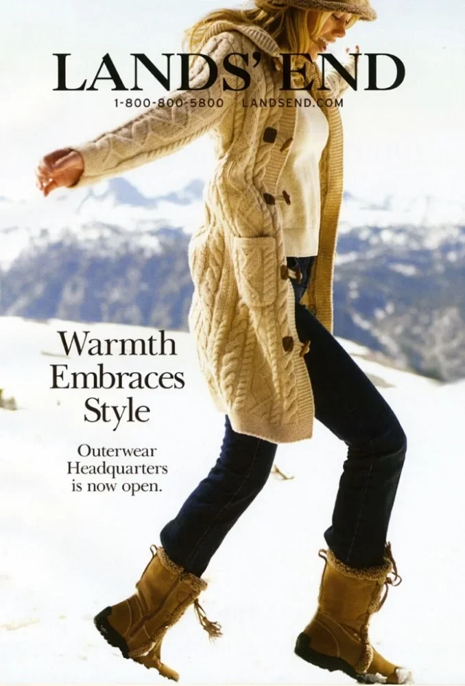 A woman in winter clothing walking in snow with mountains in background, promoting Lands' End outerwear store