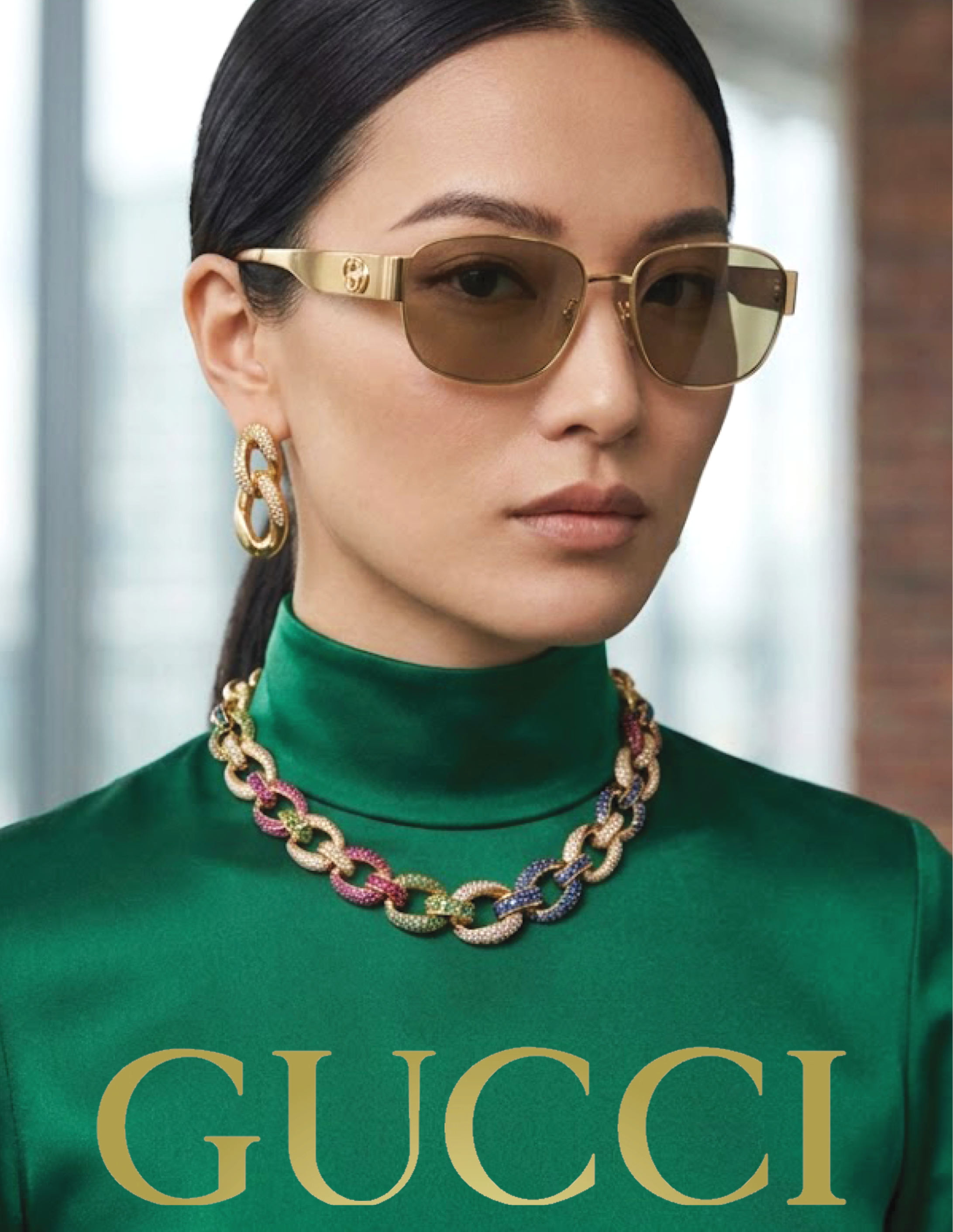 Close-up of a woman with long dark hair, tan sunglasses with gold accents, large gold earrings, a colorful chain necklace, and a green top with gold text reading 'GUCCI'.