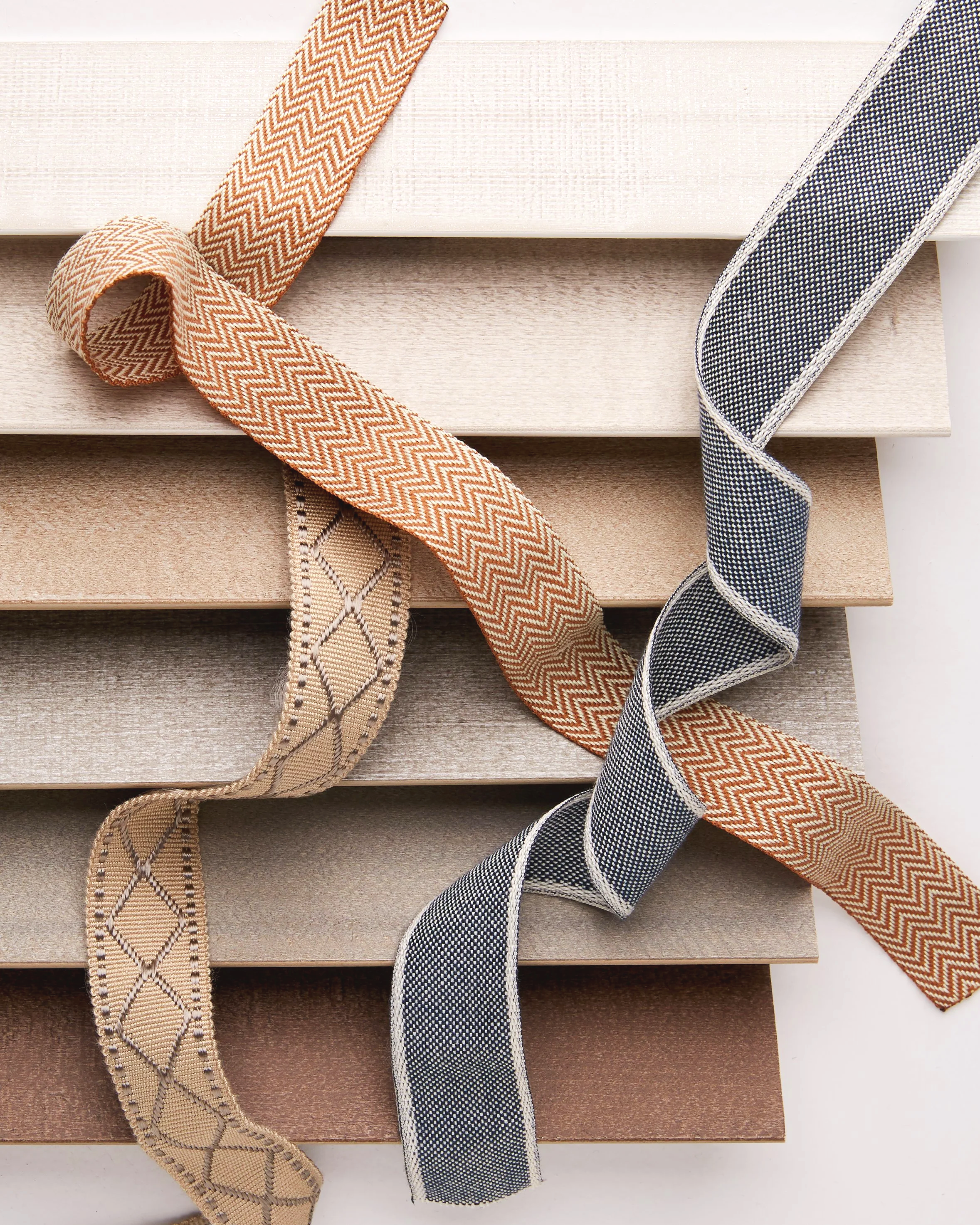Close-up of several fabric ribbons with different patterns and colors draped over wooden board samples.