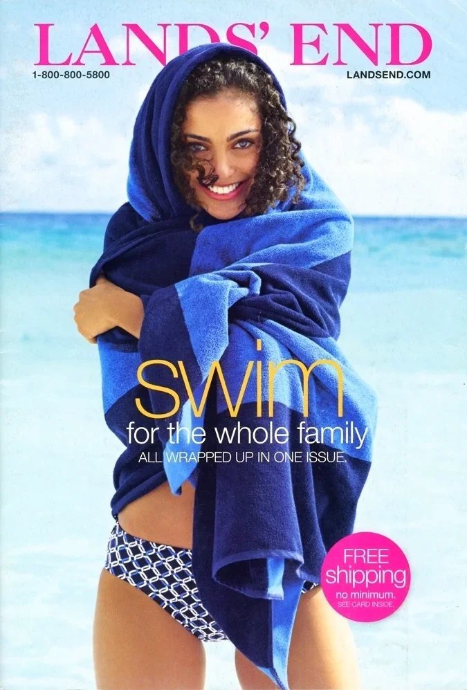 A woman at the beach wrapped in blue towels, smiling at the camera, with ocean in the background, promoting swimwear for families on a magazine cover.