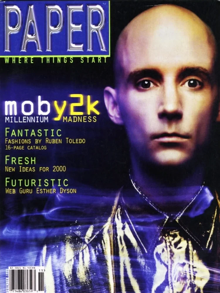 Cover of Paper magazine with a futuristic digital portrait of a person with a bald head, wearing a shiny jacket, and glowing digital effects, with headlines about millennium madness, fashion, new ideas, and a web guru.