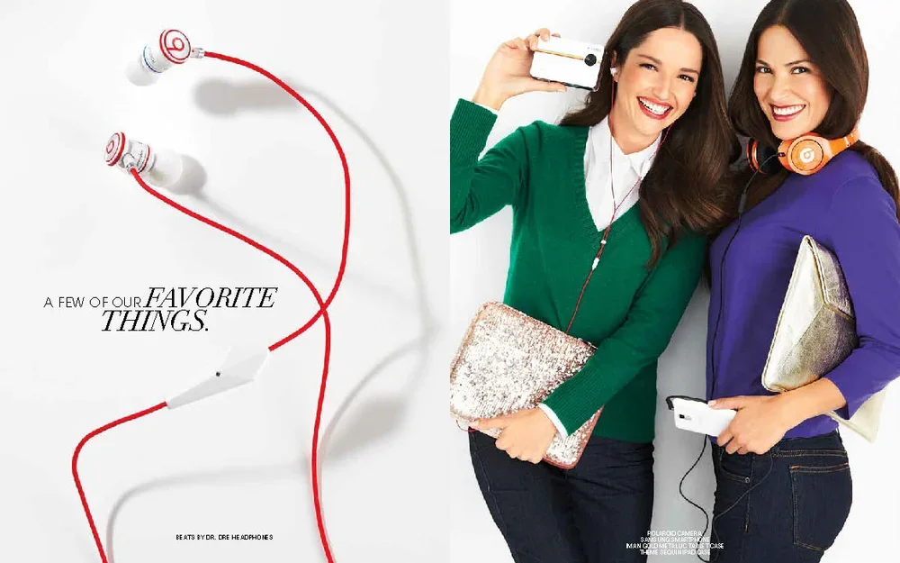Image of two women smiling, holding phones, with headphones, and a clutch, standing next to a white background with red and white earphone cables and the text 'A few of our favorite things'.