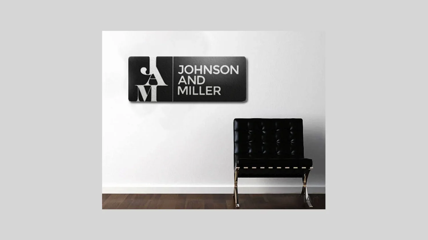 Office wall with a black and white logo reading 'Johnson and Miller' and a black leather chair with metal legs.